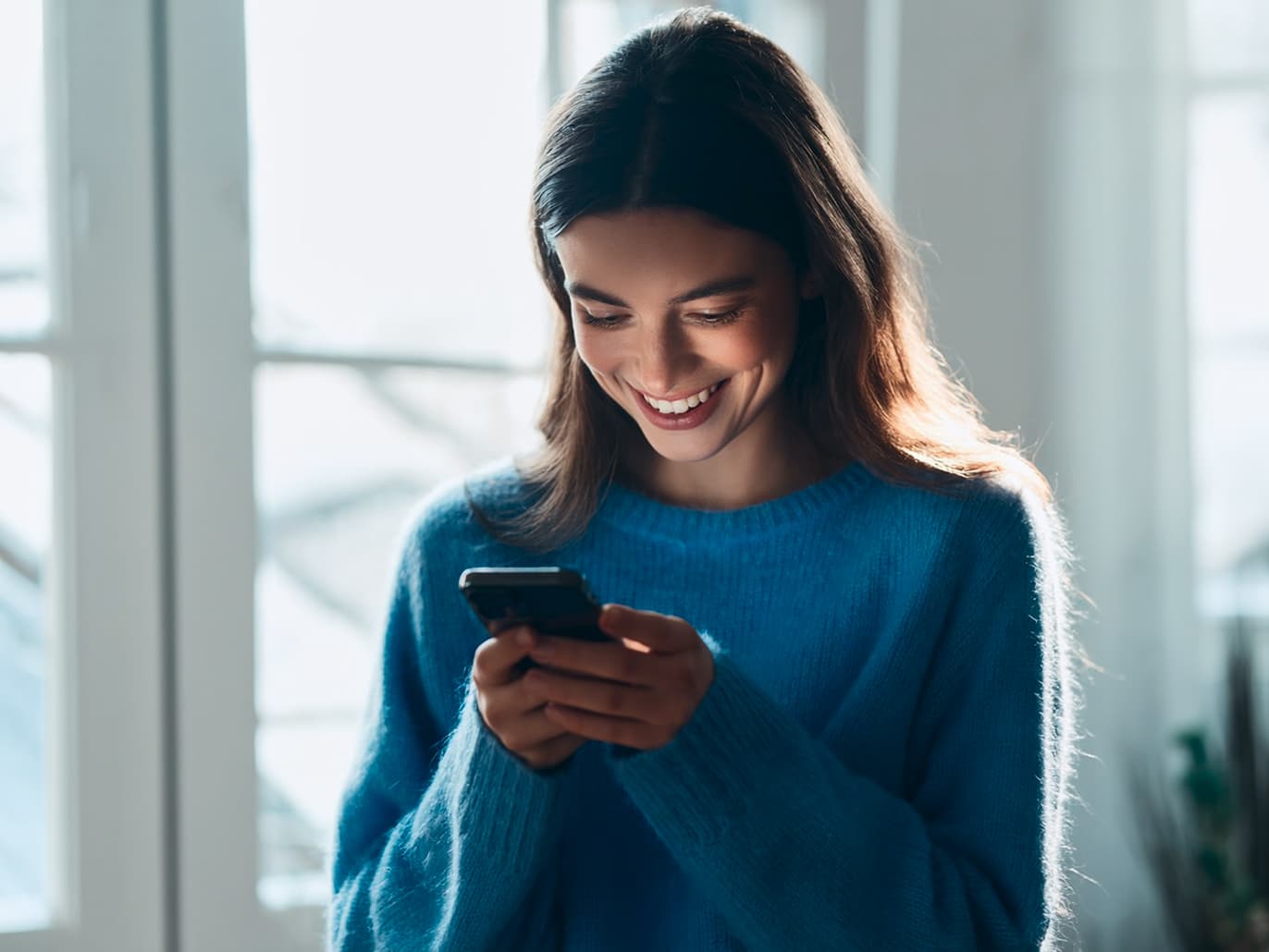 Femeie în bluză albastră consultă telefonul mobil